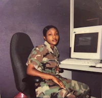 a woman in camouflage sitting in front of a computer